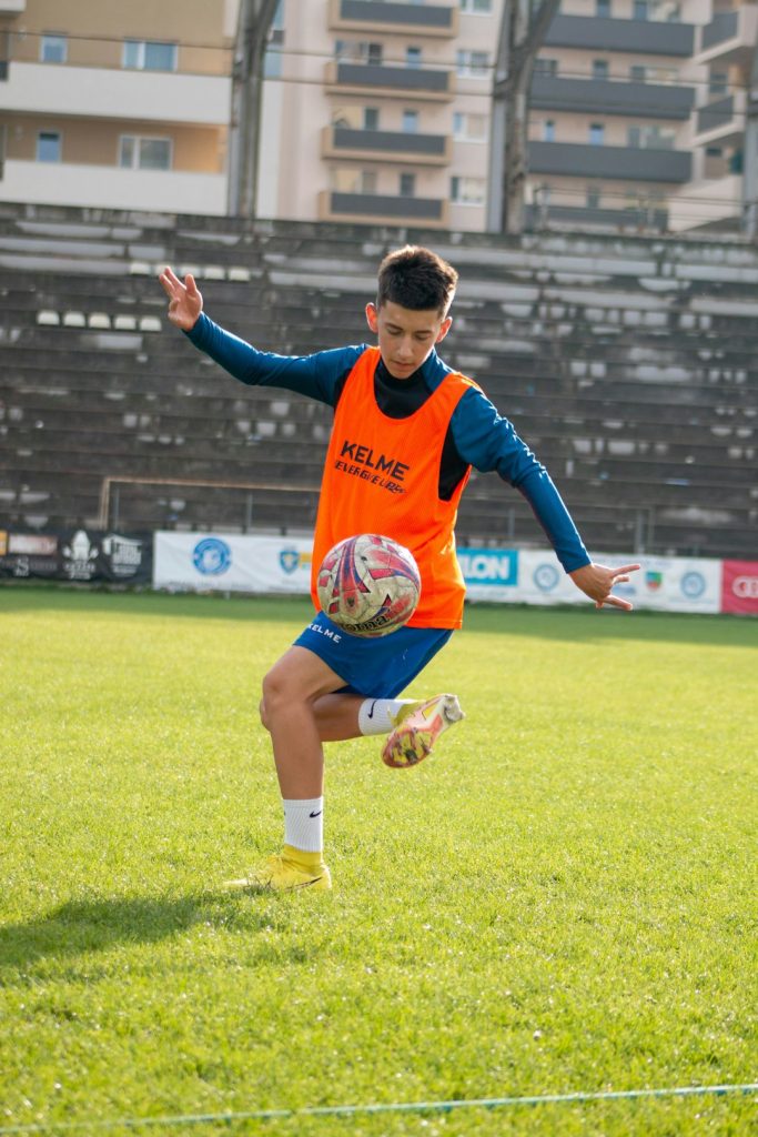 a boy in an orange shirt running on a field antonio di natale, udinese striker, italian football