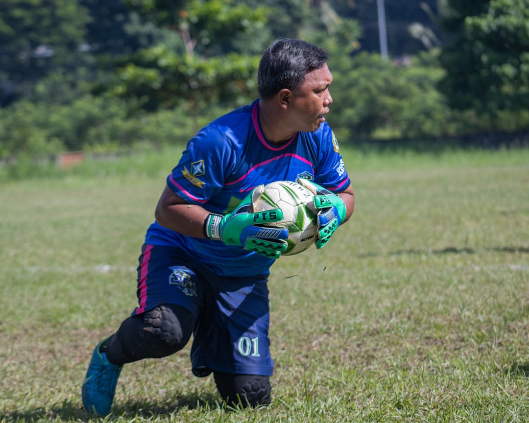 a man holding a soccer ball on top of a field goalkeeper training, reflex drills, soccer goalkeeping practice