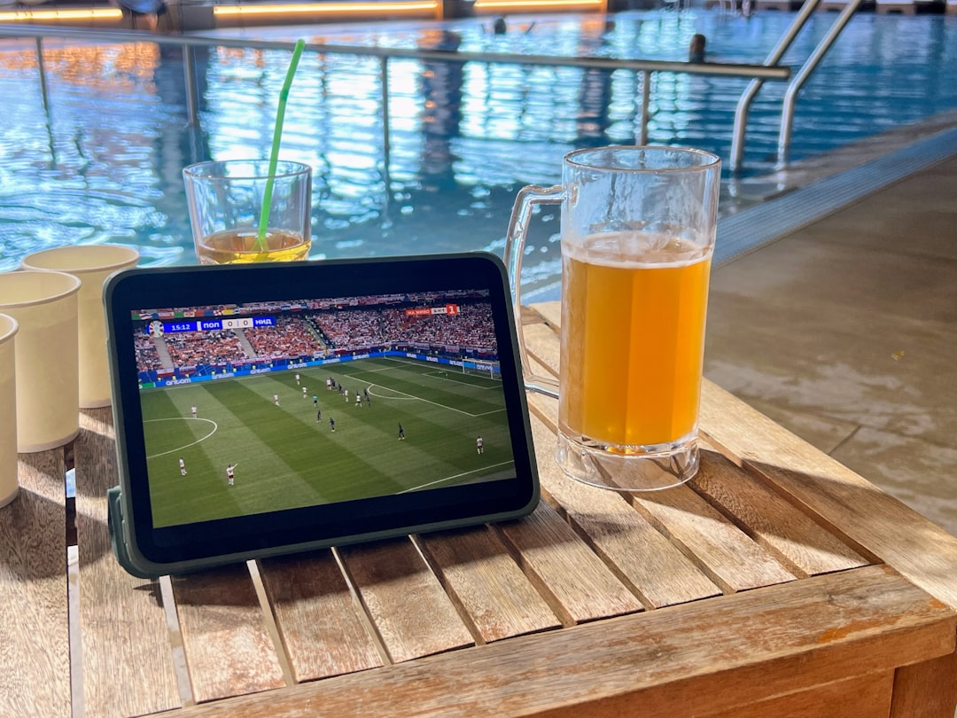 A tablet computer sitting on top of a wooden table soccer tv, streaming, watching match