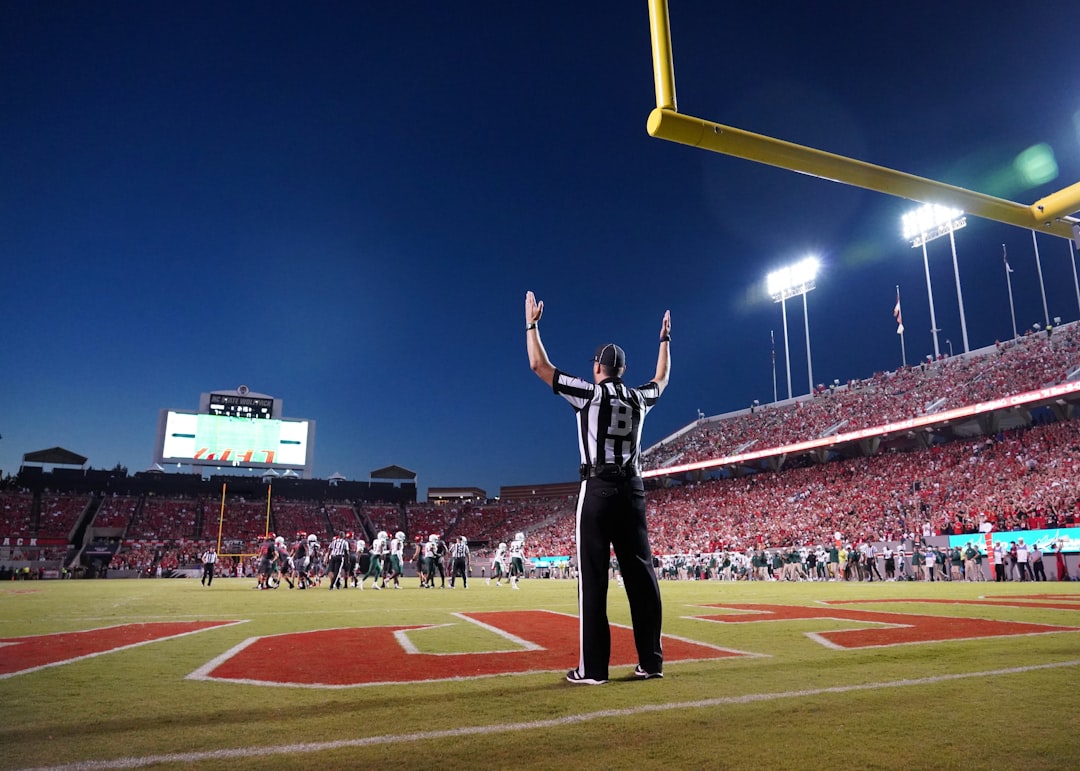 a football player standing on a field with his arms in the air american football game, stadium lights, referee whistle