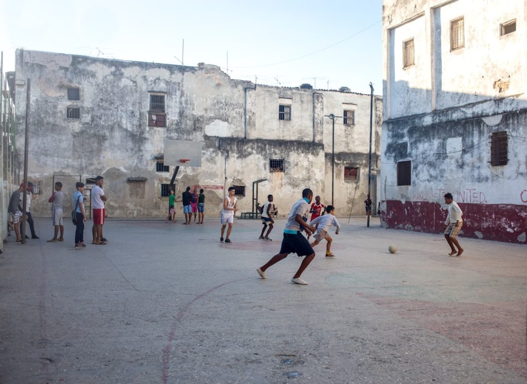 a group of people playing a game of basketball kids playing baseball, Dominican Republic, poor village