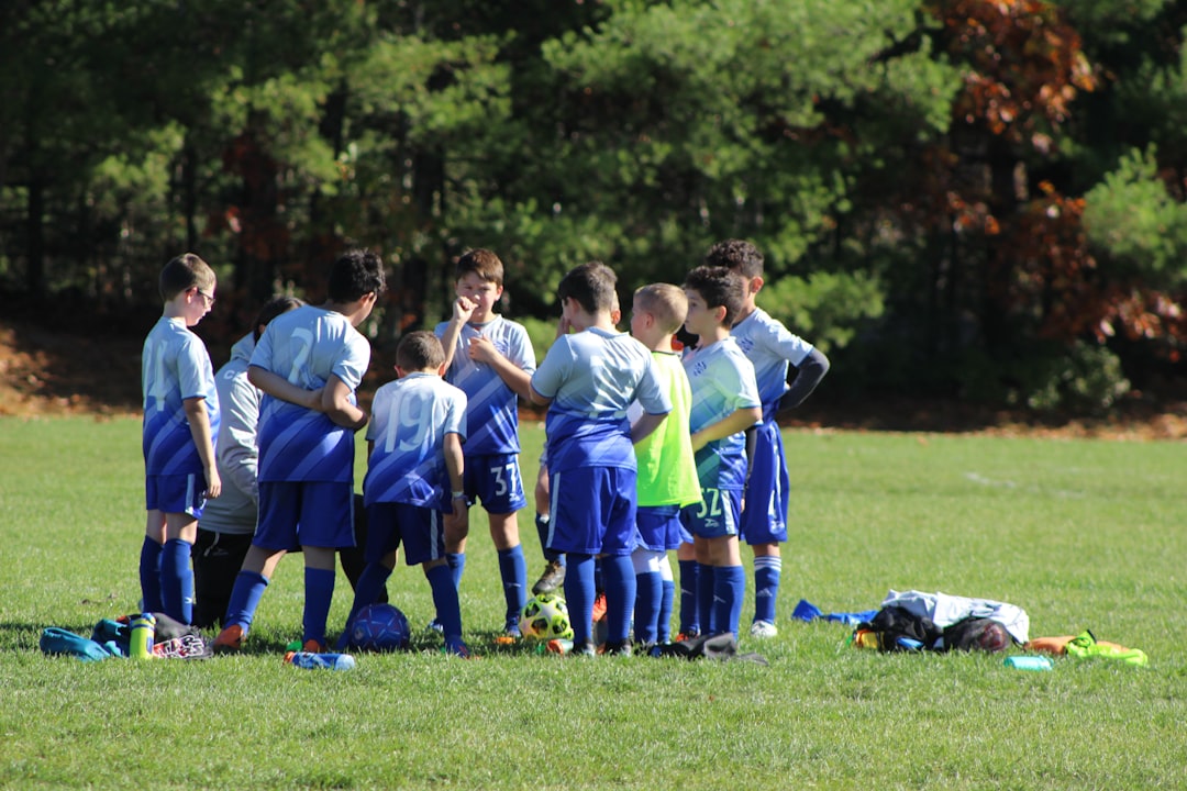 a group of young boys standing next to each other on a field football coach, play strategy, team huddle