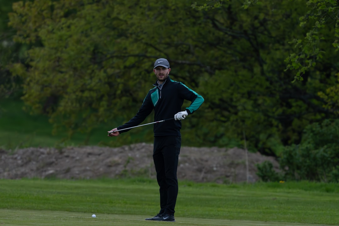 a man standing on top of a green field holding a golf club tiger woods, golf trophy, green jacket