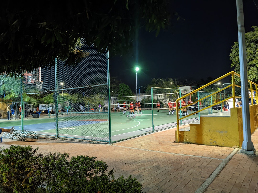 a tennis court at night with people playing cheering tennis fans,uga bulldogs tennis,college tournament