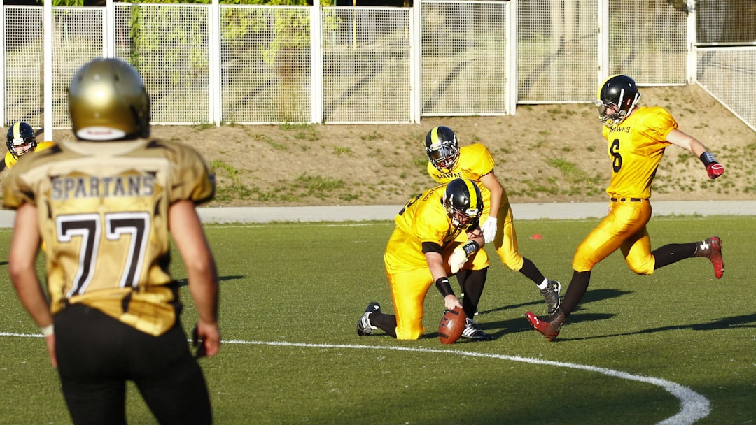 football player about to kick a football held by another player during daytime football,legendary defensive backs