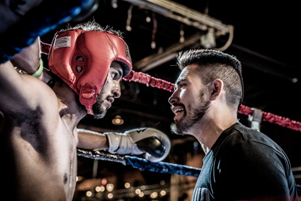 man in black talking to boxer inside ring soccer training coach player