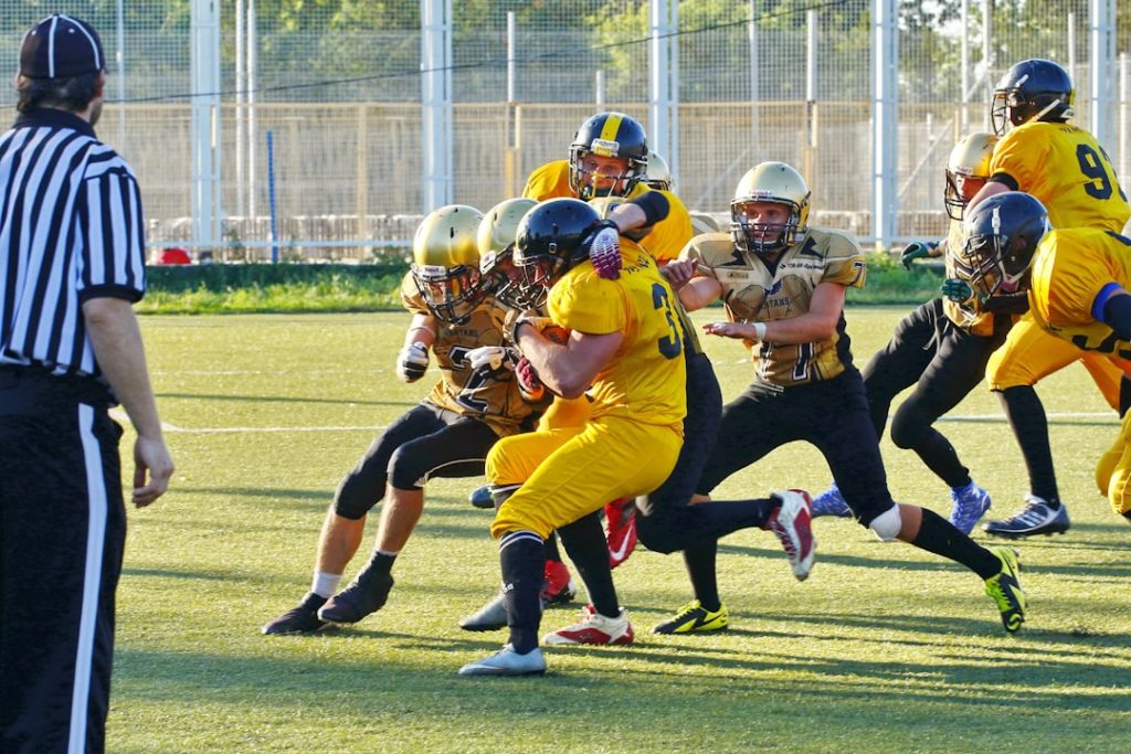 people playing american football with referee on the field during daytime football,defensive back,coverage