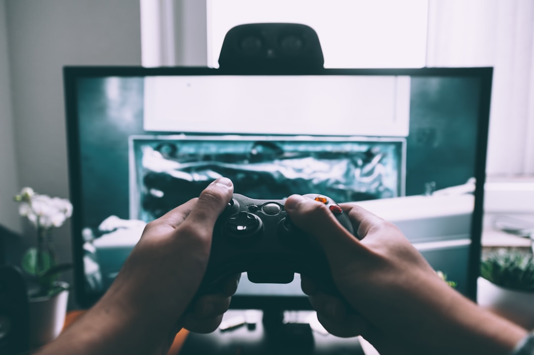 person holding game controller in front of television american football game, stadium lights, referee whistle