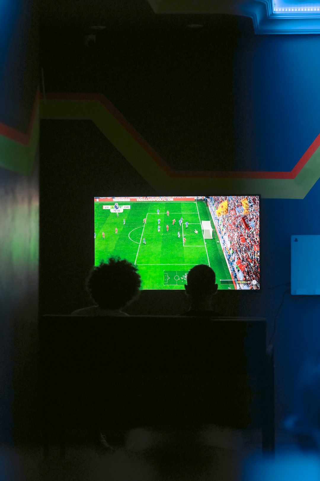 Two people watching a soccer game on a television soccer management, video game, tactics