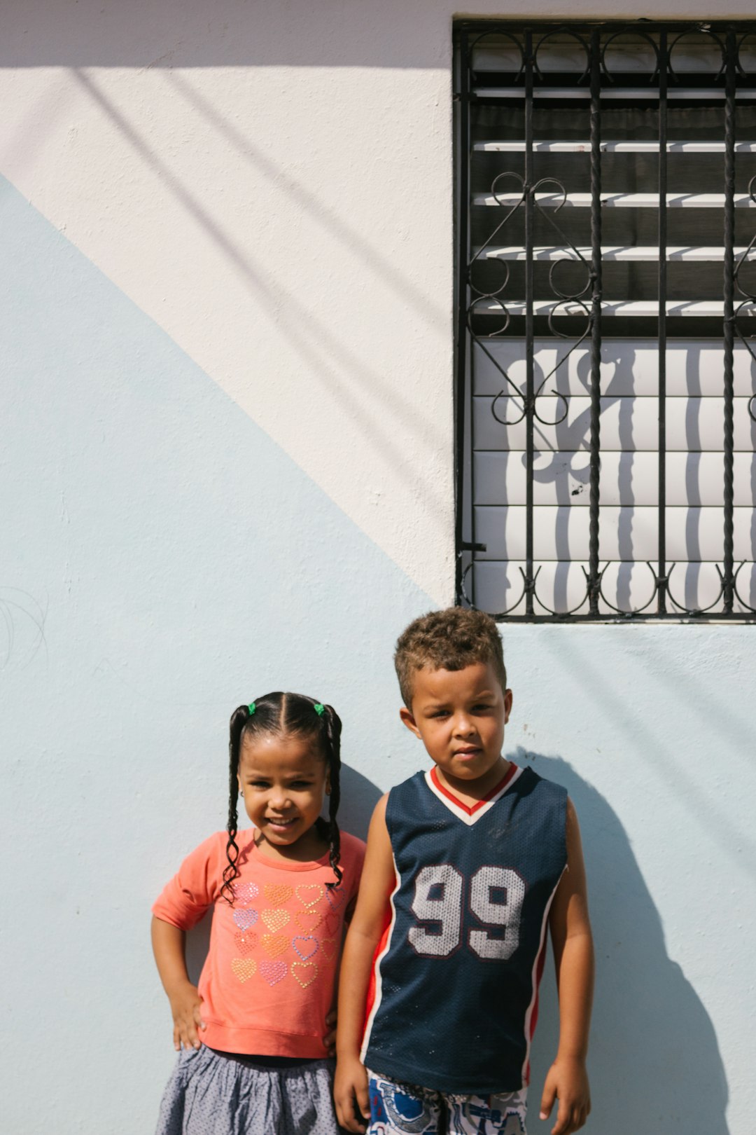 Two young children pose in front of a wall. kids playing baseball, Dominican Republic, poor village