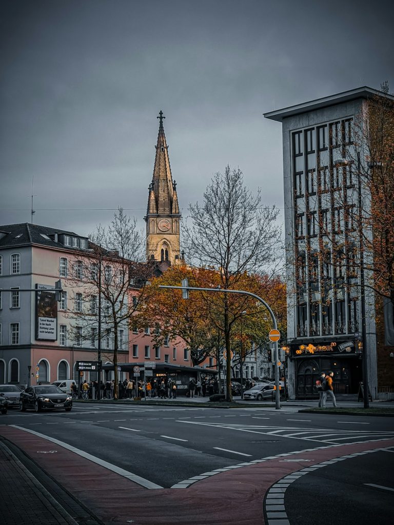 a city street with a church steeple in the background jude bellingham, borussia dortmund, football match