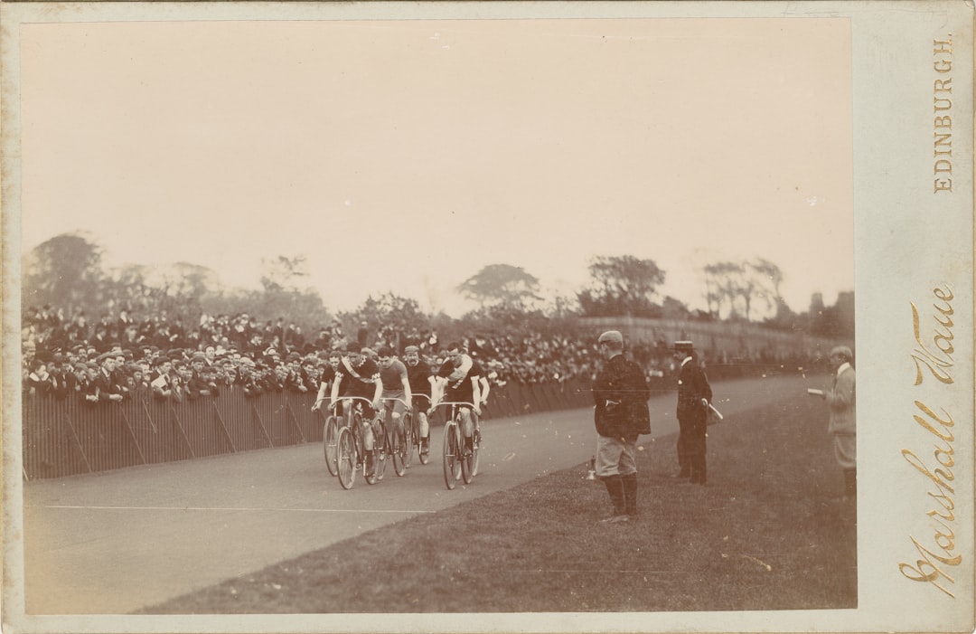 a group of people riding bikes down a road cheltenham racecourse, cheering crowd, horse racing action