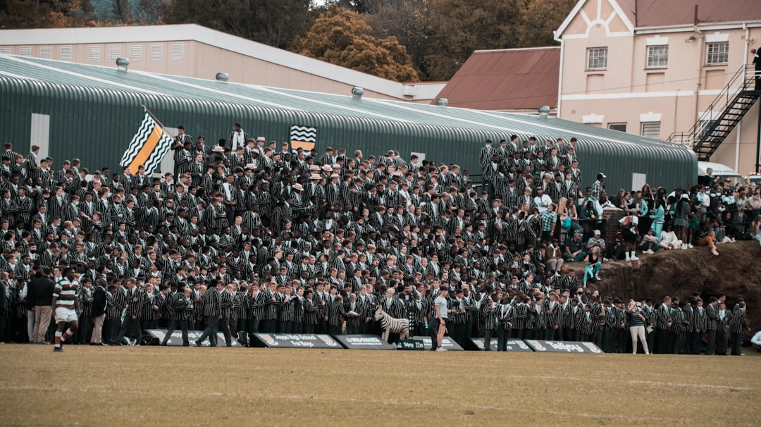 a large group of people standing in front of a building grinnell college fans cheering football game