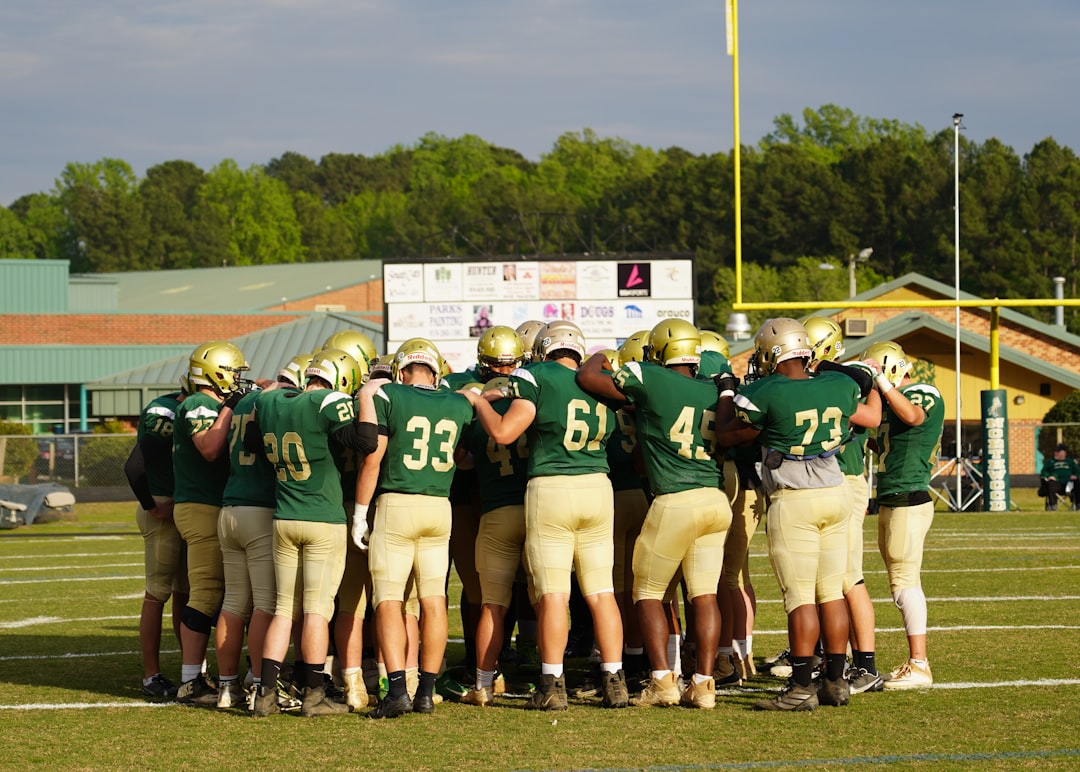 group of men in green football jersey shirt college football team huddle strategy