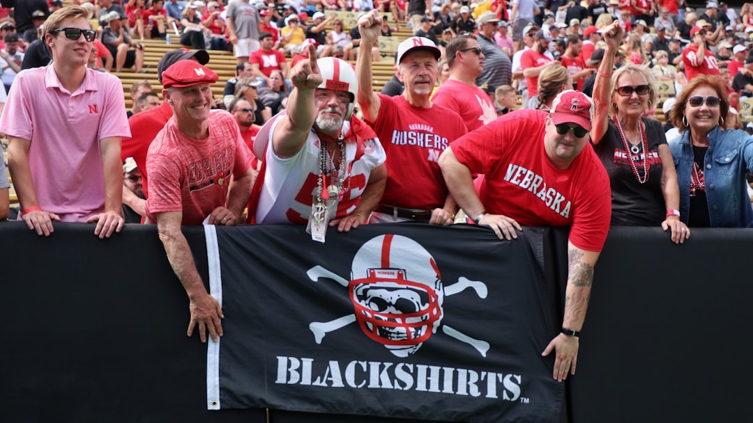 man in red crew neck t shirt standing beside man in red crew neck t shirt grinnell college fans cheering football game