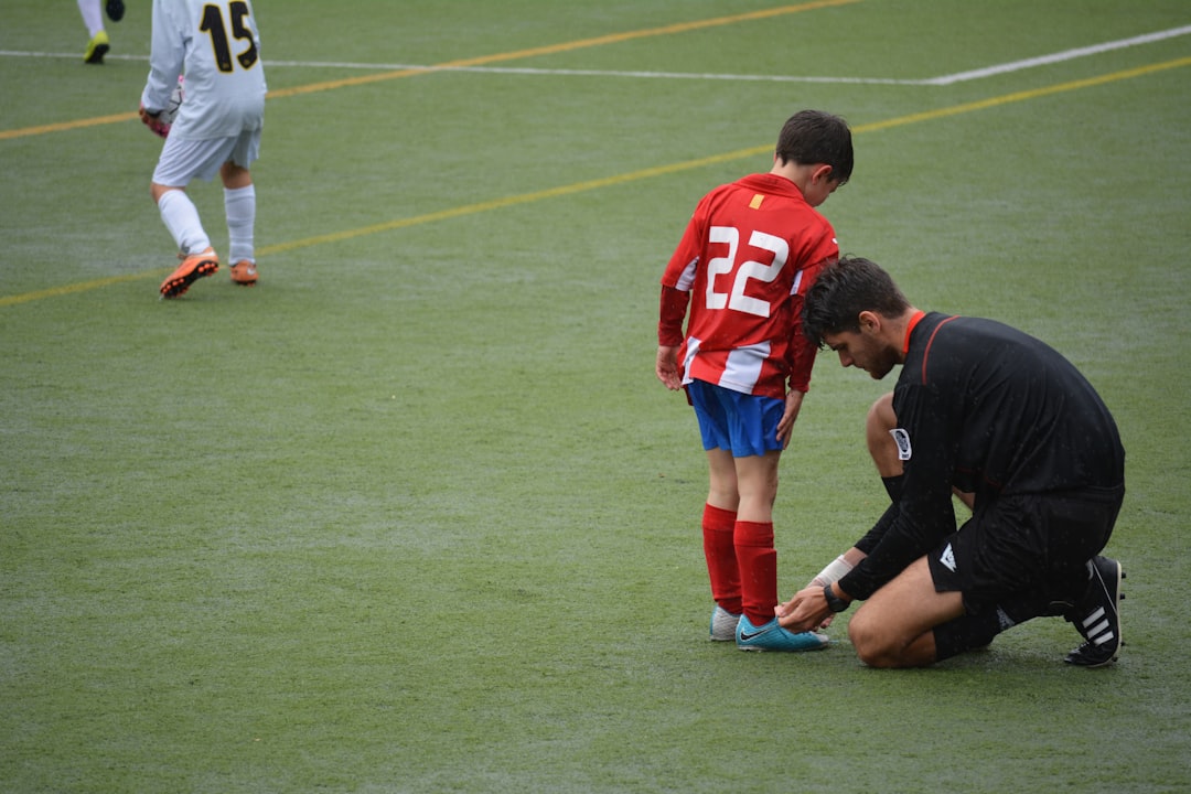 man tying boy's shoes on field football players, nfl coach, draft selection