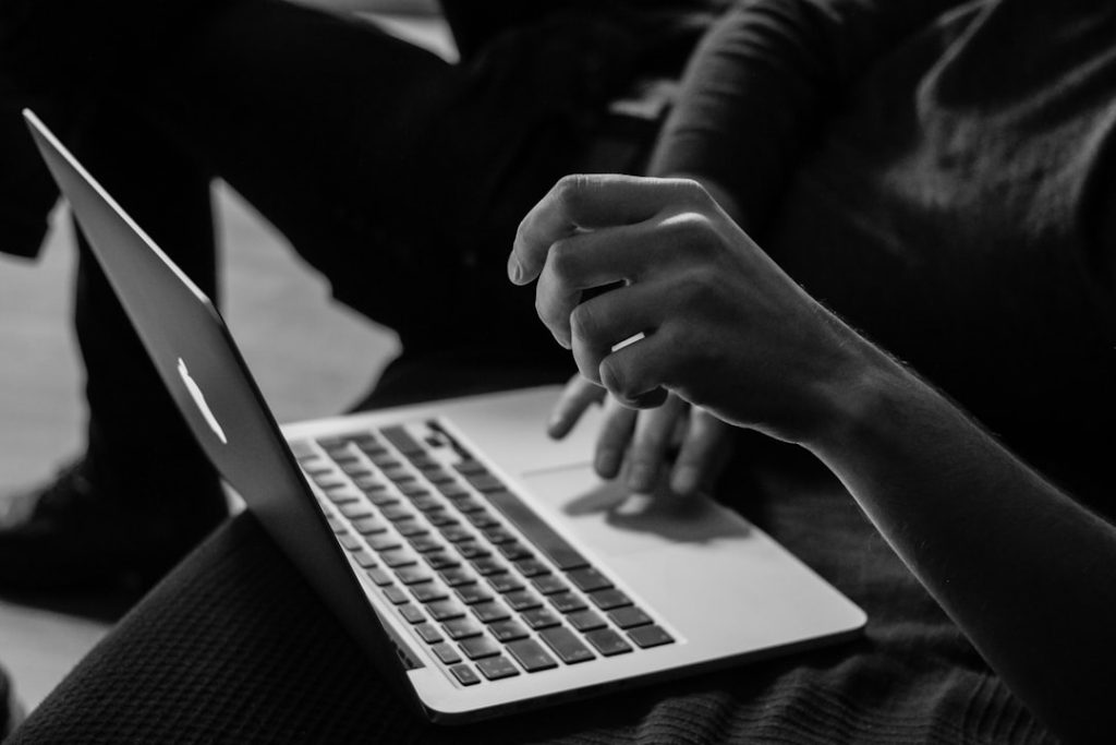 grayscale photo of person using MacBook online casino, free bonuses, slot machine