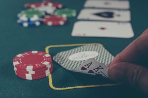 person holding black ace and king spades playing cards on poker table casino bonuses, promotions, slot spins