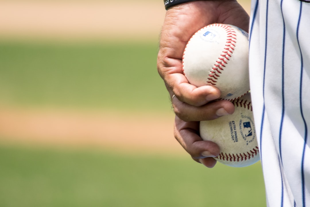 person holding two baseballs baseball scoreboard, final score, cheering fans