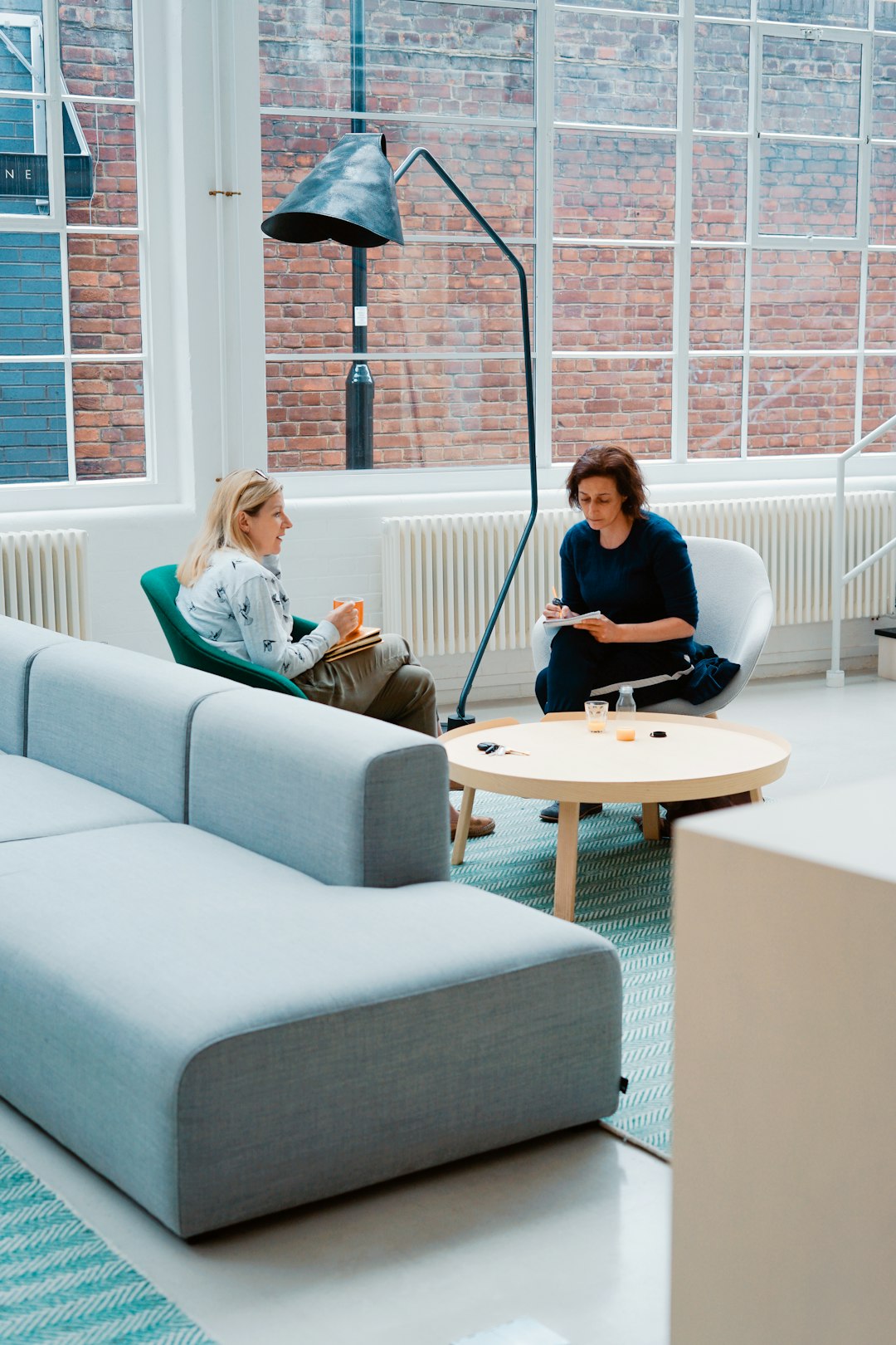 two woman sits on sofa chairs inside house client meeting, crm dashboard, commercial buildings