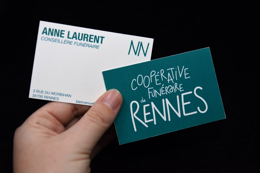 Hand holds two business cards against black background business card, recruitment, networking event
