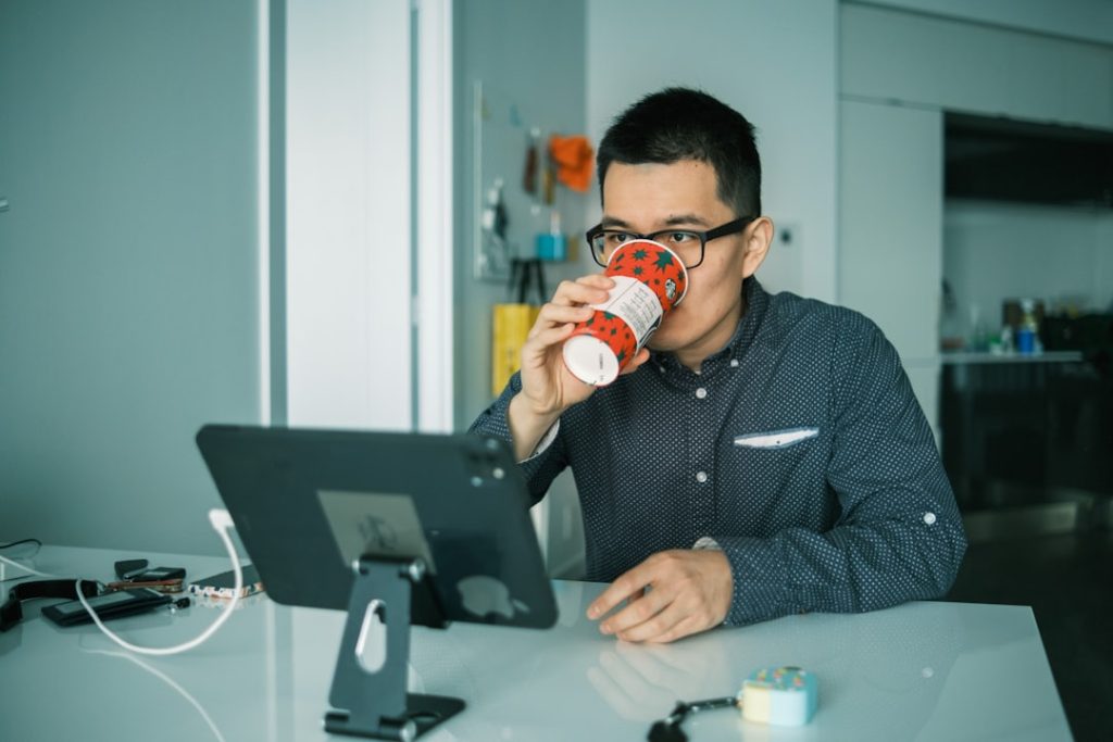 man in black and white checkered dress shirt drinking from brown and white ceramic mug mlb app, smartphone screen, restart symbol