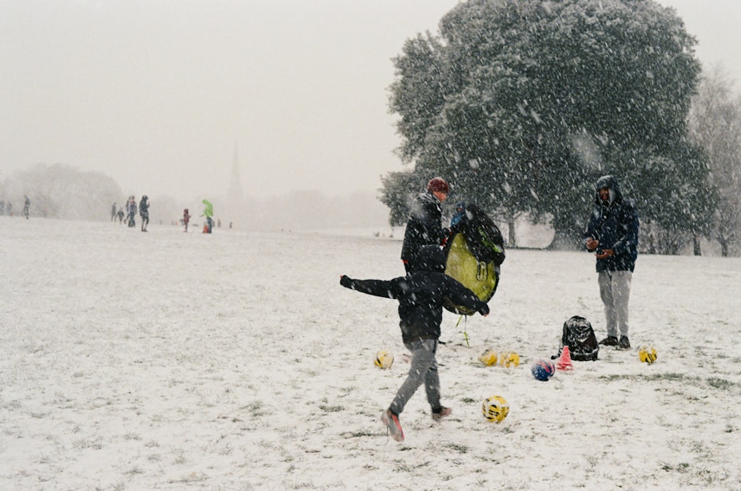 a group of people play in the snow snow football players bundled cold