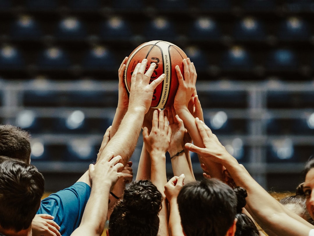 A group of people reaching for a basketball basketball game team huddle