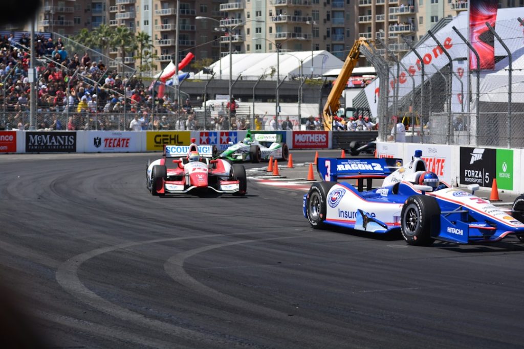 a group of racing cars driving down a race track f1 cars, formula one race, grand prix
