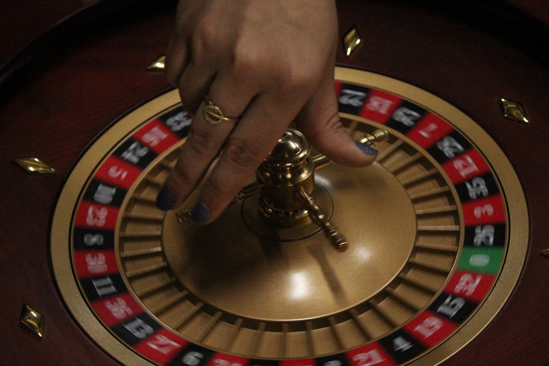 a hand holding a metal object roulette wheel, casino table, betting chips