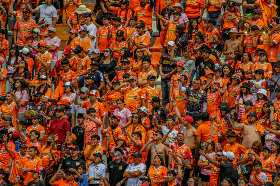 a large group of people in orange shirts leganes fans, rayo fans, stadium atmosphere