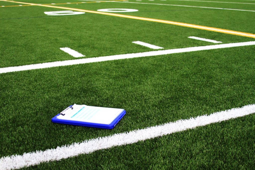 a notebook sitting on the side of a football field nfl coach strategy, salary cap management, team planning