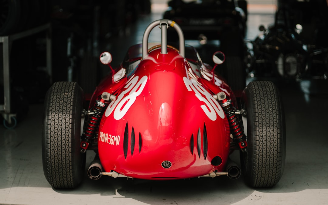 a red race car sitting in a garage f1 cars, formula one race, grand prix