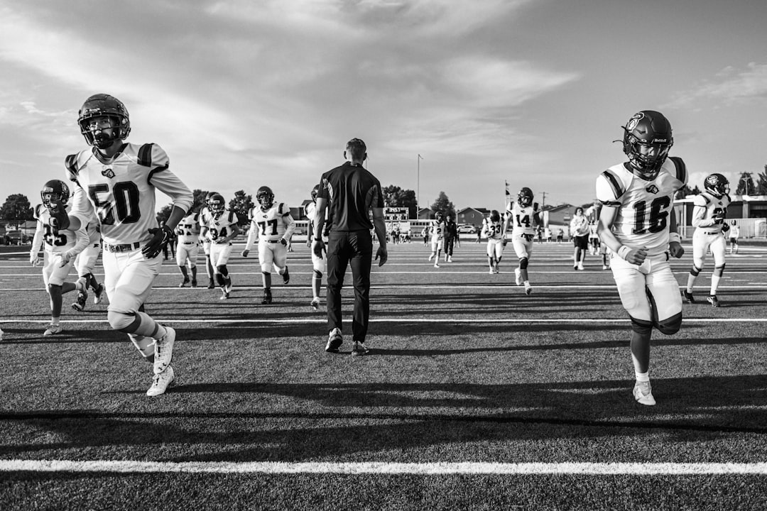 Football team runs onto the field with coach watching nfl coach strategy, salary cap management, team planning