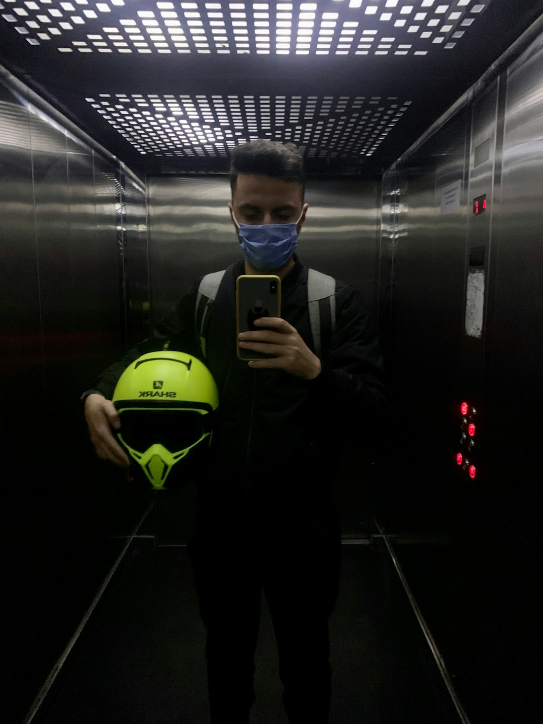 man in black suit holding green and black smartphone football helmet, soccer shin guards, player protection