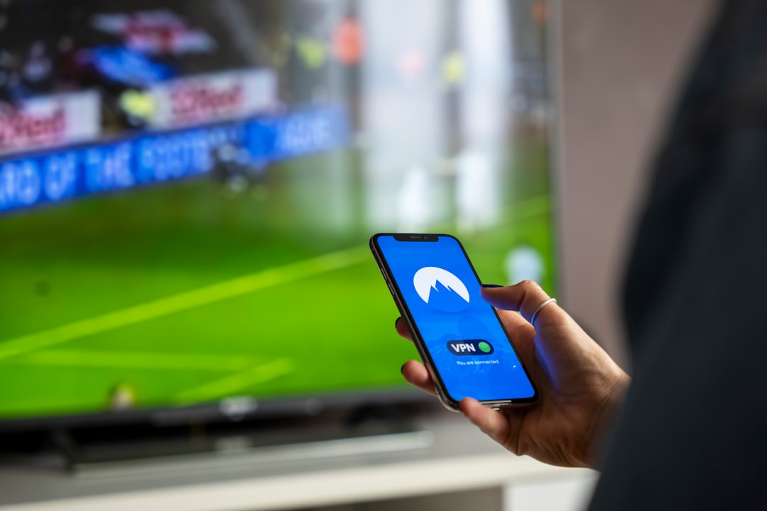 person holding iphone with blue case global watching, football on screen, vpn service