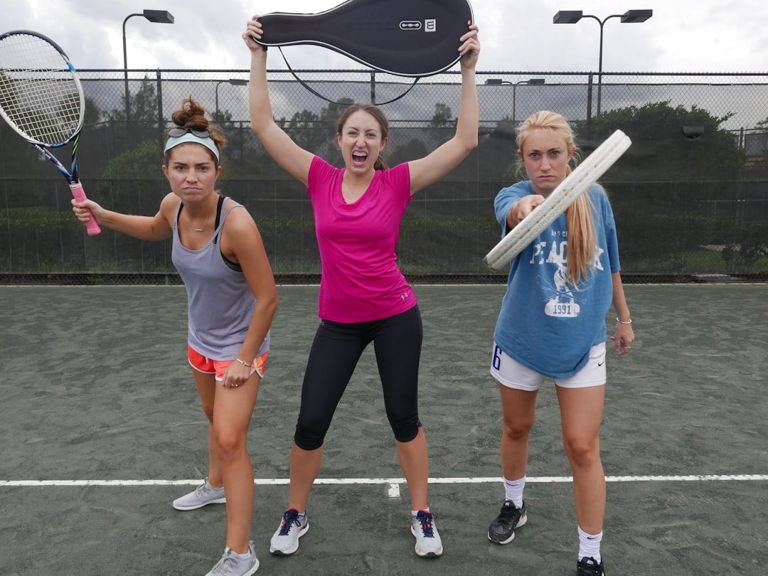 three women holding tennis rackets cheering tennis fans,uga bulldogs tennis,college tournament