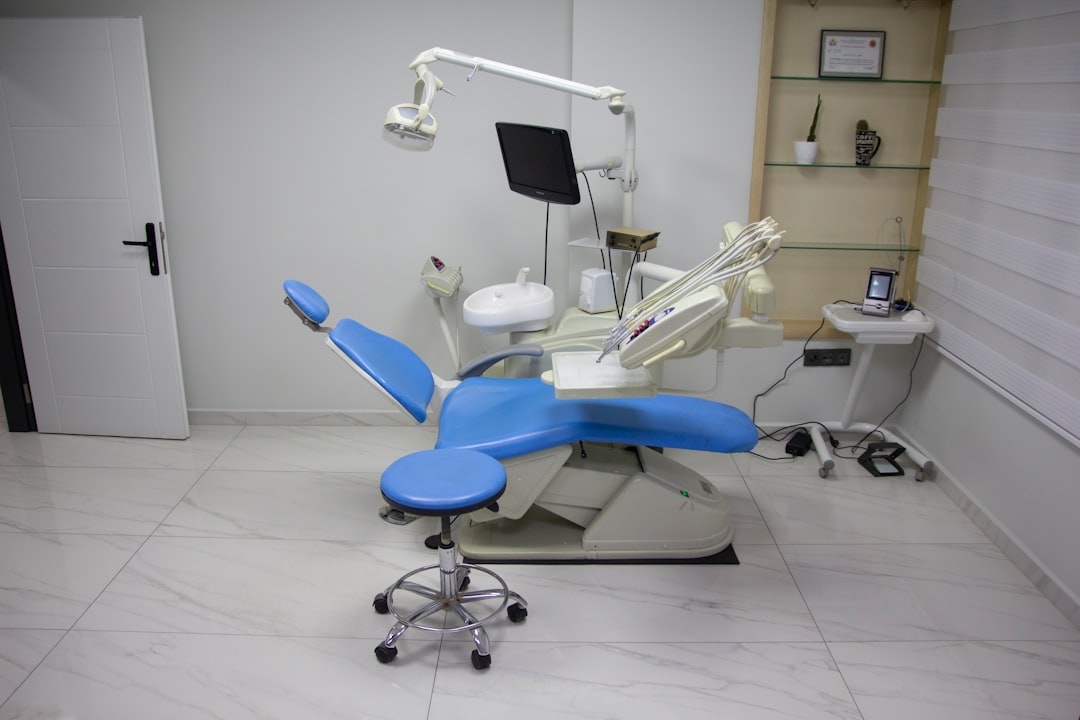 a dentist chair with a blue seat in a room clinic staff, happy client, laser treatment
