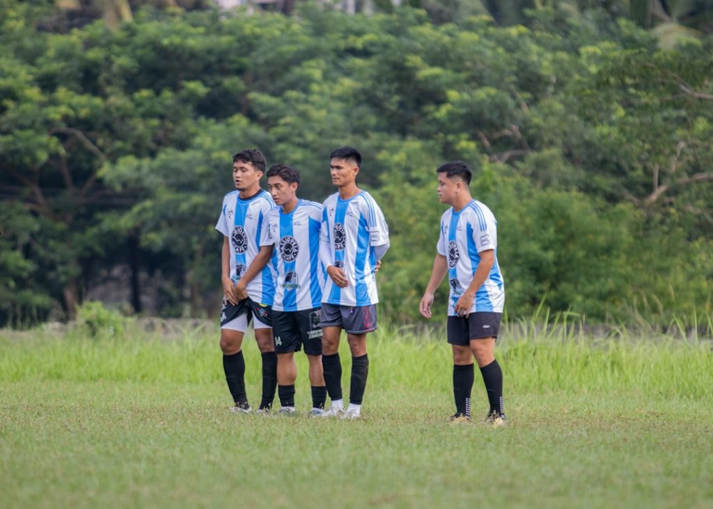 A group of young men standing next to each other on a field professional soccer training, rondo, elite team