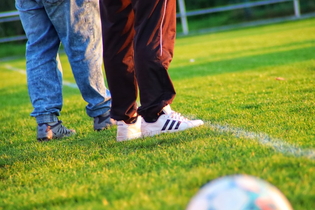 a pair of people's legs and shoes on a grass field soccer boots, professional match, athlete gear