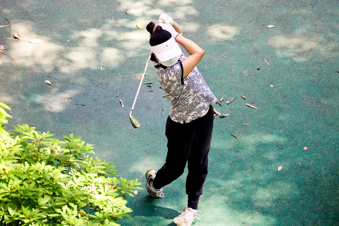 a person holding a golf club golfer putting, tournament leaderboard, golf crowd