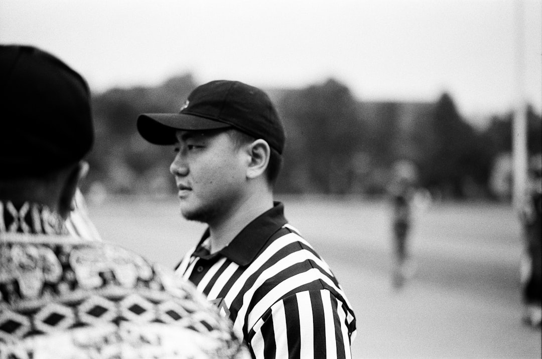 A referee stands watching a game. referee football cards players pitch sportsmanship