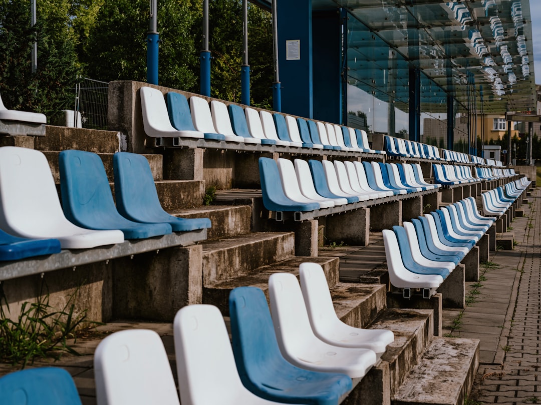 a row of blue and white chairs sitting next to each other english football stadium, matchday fans, league table