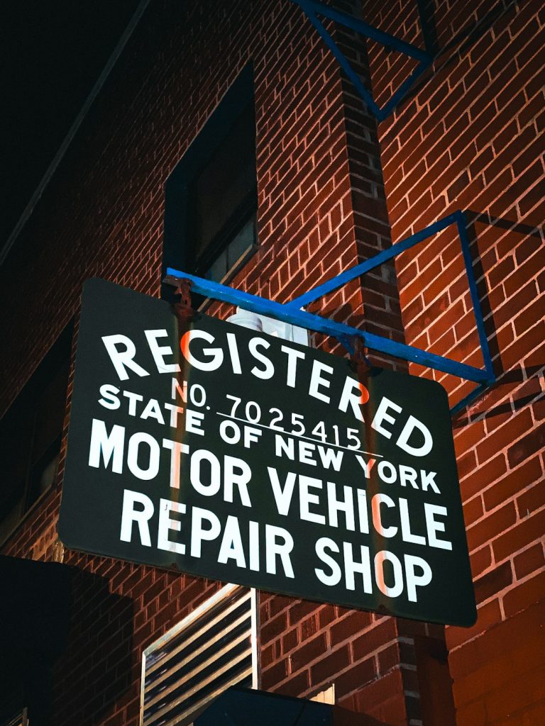 a sign on the side of a red brick building auto repair shop, new york, mechanic tools