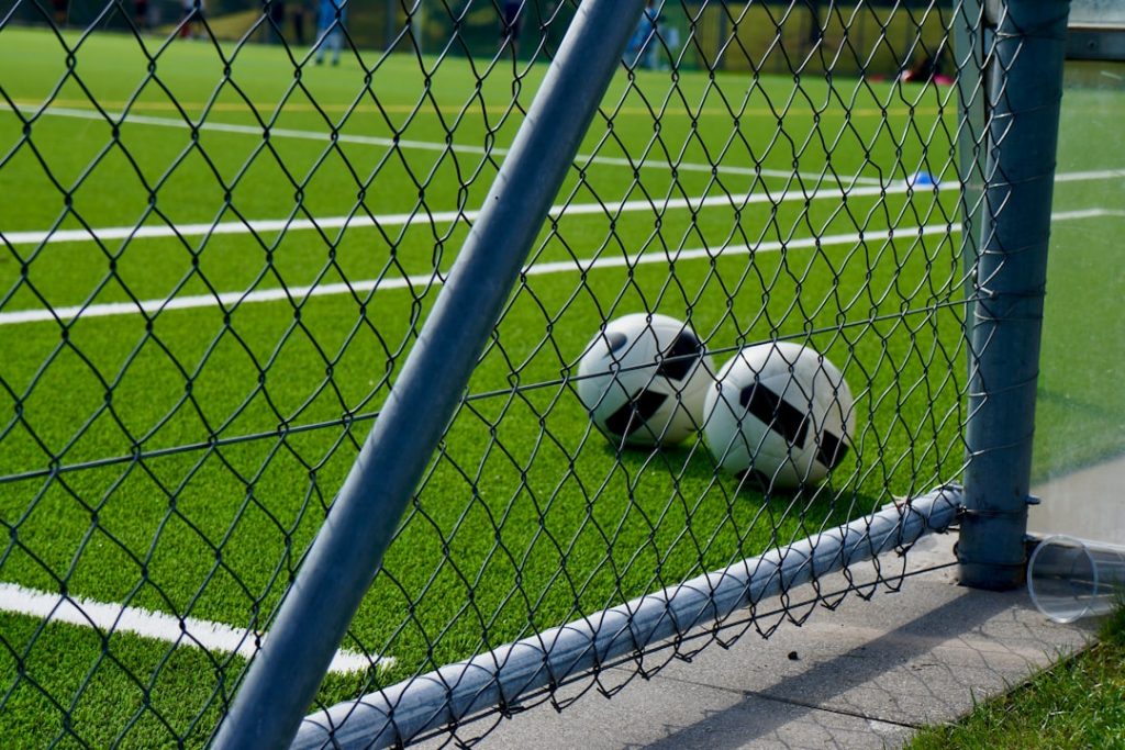 a soccer ball sitting on the ground behind a fence goalkeeper training, reflex drills, soccer goalkeeping practice