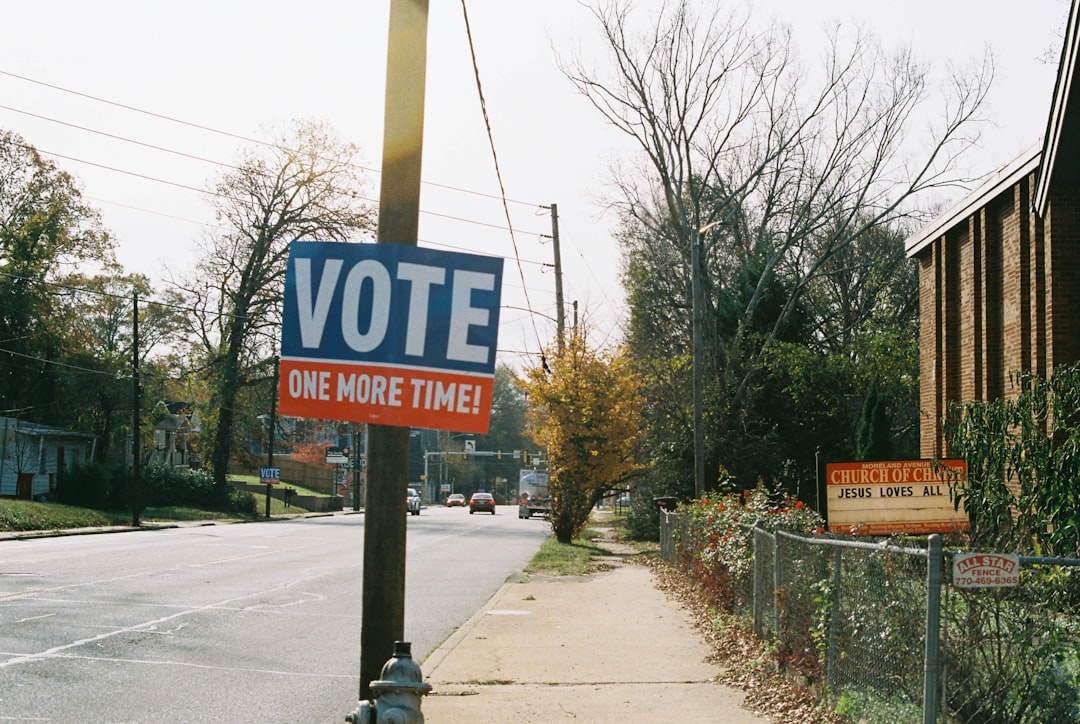 a vote sign on a pole next to a street long island map, political outreach, campaign signs