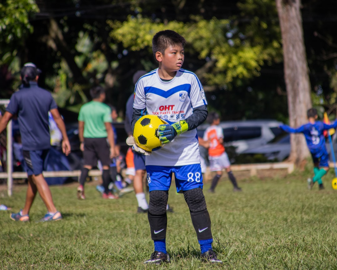 a young boy holding a soccer ball in a field football green card player fair play