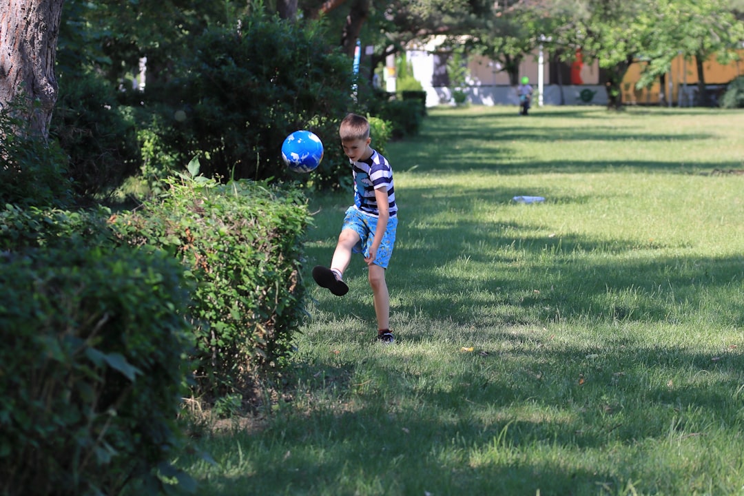 A young boy playing with a blue ball in a yard dribbling, soccer cones, backyard practice