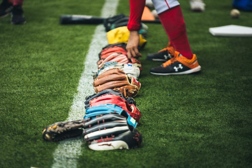 Baseball gloves are lined up on the grass field. soccer boots, professional match, athlete gear
