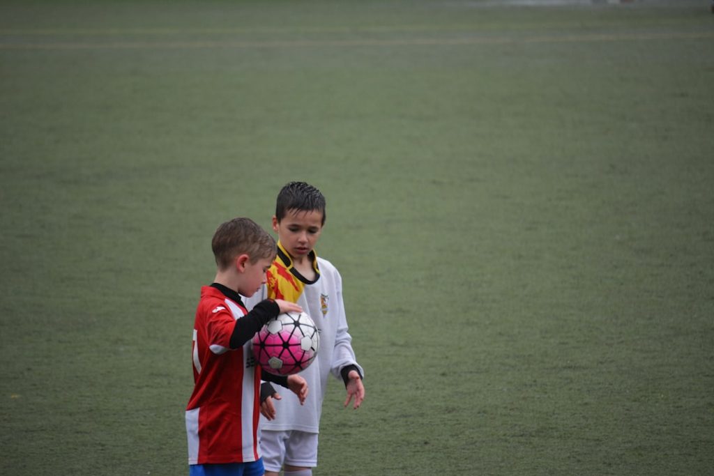 boy holding soccer ball beside other ball on soccer field ronaldo messi football rivalry